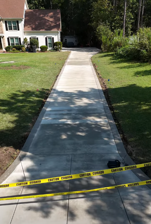 Newly installed concrete sidewalk through a lawn, marked off with caution tape in Fayetteville, NC