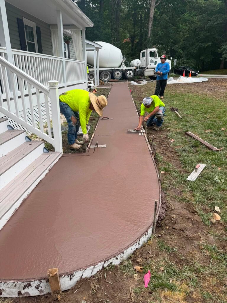 Crew installing a decorative red-tinted concrete walkway in Fayetteville, NC